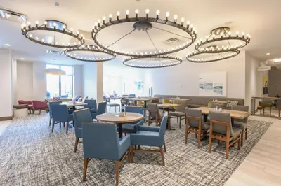 a dining room with tables and chairs and a chandelier at Hilton Garden Inn Cincinnati Midtown in Cincinnati