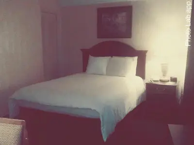 a bedroom with a bed with white sheets and pillows at Hillside Inn in Madison