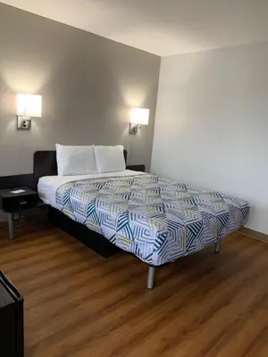 a bed in a room with two lamps and a wooden floor at Motel 6-Dayton, OH in Dayton