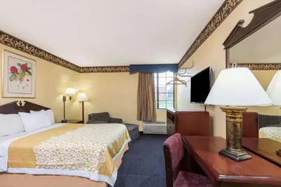 a hotel room with a bed and a desk and a television at Days Inn & Suites by Wyndham Youngstown / Girard Ohio in Girard