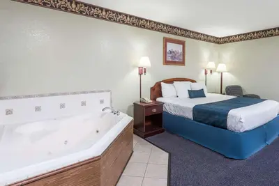a hotel room with a bed and a bath tub at Days Inn & Suites by Wyndham Youngstown / Girard Ohio in Girard