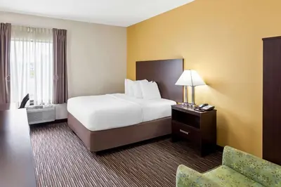 a hotel room with a bed and a chair at SureStay by Best Western Grayson in Grayson