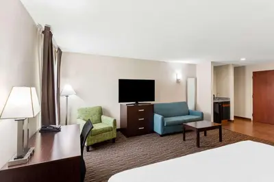a hotel room with a bed and a couch and a tv at SureStay by Best Western Grayson in Grayson