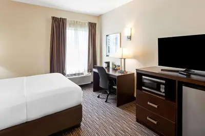 a hotel room with a bed and a desk with a television at SureStay by Best Western Grayson in Grayson