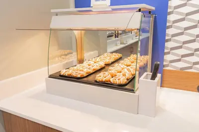 a display case filled with lots of glazed donuts at Holiday Inn Express & Suites - Marion by IHG in Marion