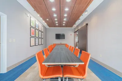a conference room with a table and orange chairs at Holiday Inn Express & Suites - Marion by IHG in Marion