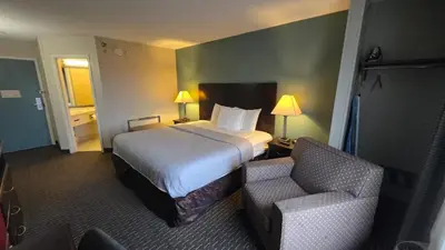 a hotel room with a bed and a chair at Copley Inn & Suites By OYO Akron OH in Akron