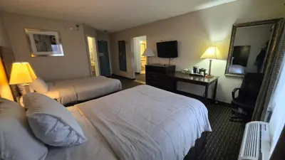 a hotel room with two beds and a mirror at Copley Inn & Suites By OYO Akron OH in Akron