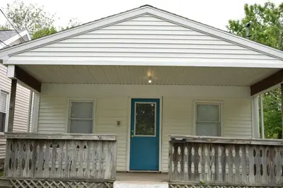 a house with a blue door and a wooden fence at Cozy 2 Bedroom House in Adrian