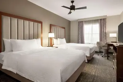 a hotel room with two beds and a desk at Homewood Suites Fort Wayne in Fort Wayne