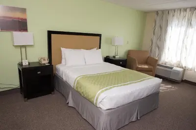 a hotel room with a large bed and a chair at Hope Hotel and Richard C. Holbrooke Conference Center in Fairborn