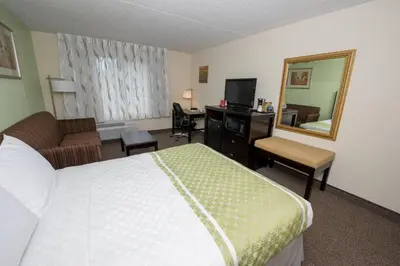 a hotel room with a bed and a desk and a mirror at Hope Hotel and Richard C. Holbrooke Conference Center in Fairborn