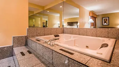 a bath tub in a bathroom with a large mirror at Best Western Muncie in Muncie