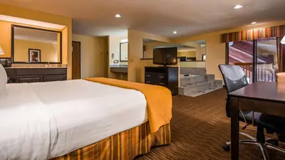 a hotel room with a large bed and a dining room at Best Western Muncie in Muncie