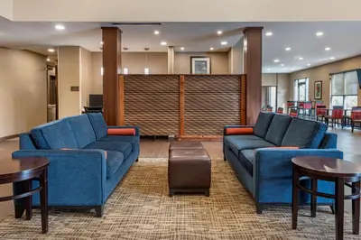 a lobby with blue couches and tables and chairs at Comfort Suites Columbus Airport in Columbus