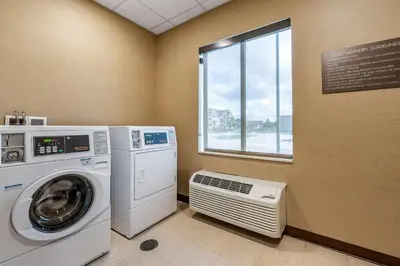 a laundry room with a washing machine and a window at Comfort Suites Columbus Airport in Columbus