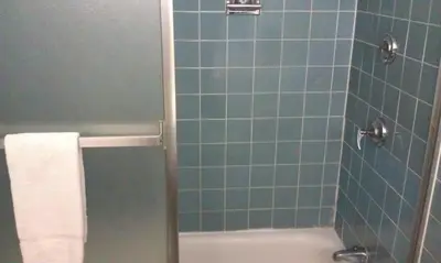 a bathroom with a blue tiled shower with a white towel at Kings Inn Cleveland in Strongsville