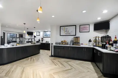 a kitchen with black cabinets and wooden floors at Staybridge Suites Toledo/Maumee by IHG in Maumee