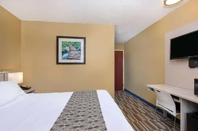 a hotel room with a bed and a flat screen tv at Microtel Inn & Suites by Wyndham Dry Ridge in Dry Ridge