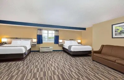 a hotel room with two beds and a couch at Microtel Inn & Suites by Wyndham Dry Ridge in Dry Ridge