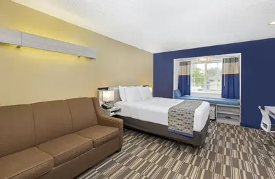 a hotel room with a bed and a couch at Microtel Inn & Suites by Wyndham Dry Ridge in Dry Ridge