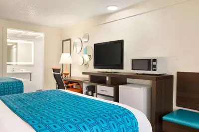 a hotel room with a bed and a flat screen tv at Dover Inn and Suites in Dover