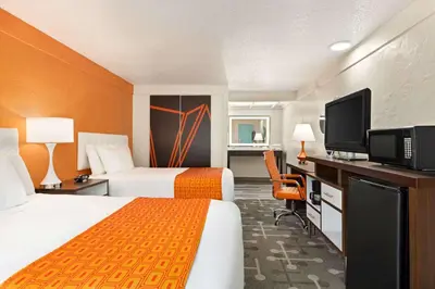 a hotel room with two beds and a flat screen tv at Dover Inn and Suites in Dover
