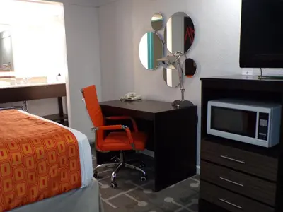 a bedroom with a desk and a bed and a tv at Dover Inn and Suites in Dover