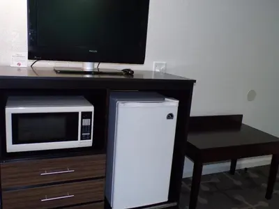 a microwave and a television on a table with a refrigerator at Dover Inn and Suites in Dover