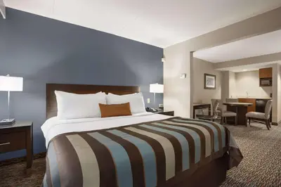 a hotel room with a large bed and a desk at Wingate by Wyndham Sylvania-Toledo in Sylvania