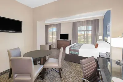 a hotel room with a bed and a table and chairs at Wingate by Wyndham Sylvania-Toledo in Sylvania