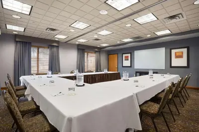 a conference room with tables and chairs and a screen at Wingate by Wyndham Sylvania-Toledo in Sylvania