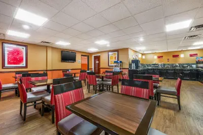 a restaurant with wooden tables and chairs and a television at Best Western Plus Georgetown Corporate Center Hotel in Georgetown