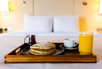 a tray with a plate of pancakes and a glass of orange juice at Crowne Plaza Cleveland at Playhouse Square by IHG in Cleveland
