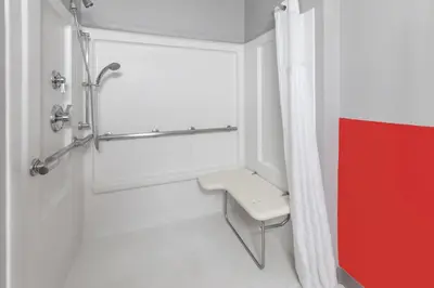 a bathroom with a shower with a bench in it at Super 8 by Wyndham Kent/Akron Area in Kent