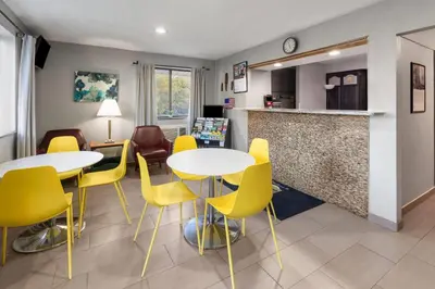 a waiting room with two tables and yellow chairs at Super 8 by Wyndham Kent/Akron Area in Kent