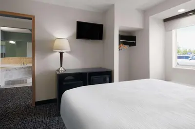 a bedroom with a bed and a bathroom with a tub at Baymont by Wyndham Boardman in Boardman