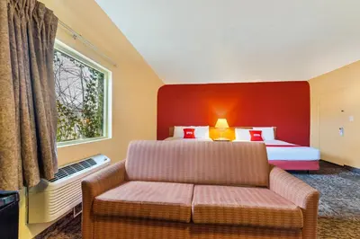 a bedroom with a bed and a couch and a window at OYO Hotel North Lima OH - Boardman in North Lima