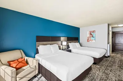 a hotel room with two beds and a chair at Best Western Fort Wayne Inn & Suites North in Fort Wayne
