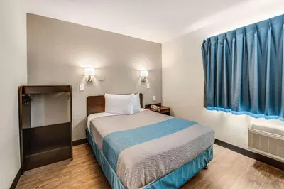 a small room with a bed and blue curtains at Motel 6-Fort Wayne, IN in Fort Wayne