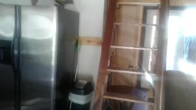 a kitchen with a ladder next to a refrigerator at Tranquil Waters Cabin in Frenchburg