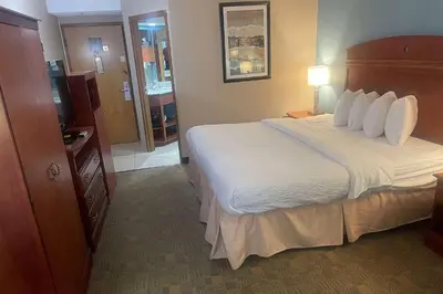 a hotel room with a large bed and a bathroom at Days Inn by Wyndham Englewood Dayton Airport in Dayton