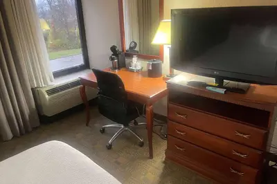 a desk with a television and a chair in a room at Days Inn by Wyndham Englewood Dayton Airport in Dayton