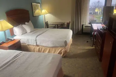 a hotel room with two beds and a desk at Days Inn by Wyndham Englewood Dayton Airport in Dayton