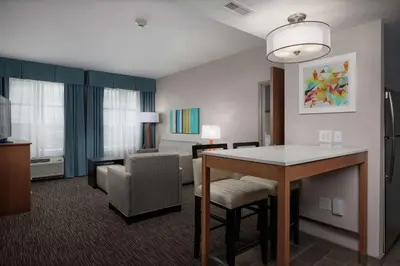 a hotel room with a table and a living room at Homewood Suites By Hilton Cincinnati Midtown in Cincinnati