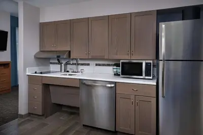 a kitchen with wooden cabinets and a stainless steel refrigerator at Homewood Suites By Hilton Cincinnati Midtown in Cincinnati