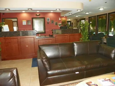 a living room with a leather couch and a bar at Royalton Inn & Suites Upper Sandusky in Upper Sandusky