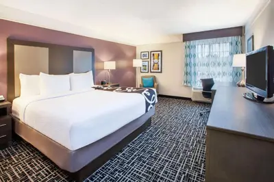a hotel room with a large bed and a flat screen tv at La Quinta by Wyndham Cincinnati Airport Florence in Florence
