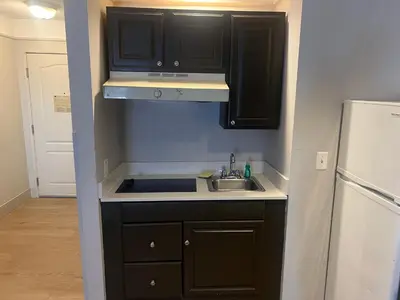 a kitchen with black cabinets and a sink and a refrigerator at La Quinta by Wyndham Cincinnati Airport Florence in Florence