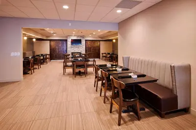 a dining room with tables and chairs and a couch at Four Points by Sheraton Cleveland-Eastlake in Eastlake